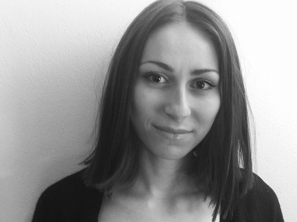 Ein schwarz-weiß Bild einer jungen Frau mit schulterlangen Haaren, die freundlich in die Kamera lächelt.