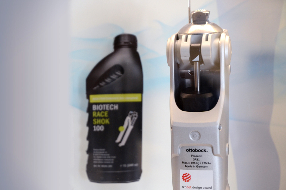 Im Vordergrund ist die Kniegelenksprothese zu sehen, im Hintergrund steht eine kleine Flasche des  Bio-Hydrauliköls.