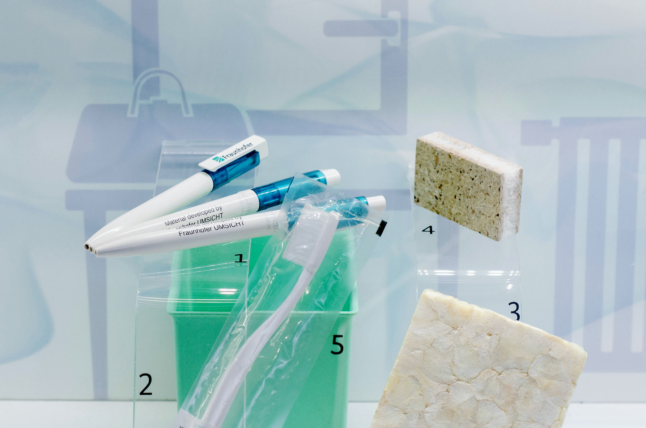 Drei Kugelschreiber, eine Zahnbürste und zwei Boxen aus Biokunststoffen.