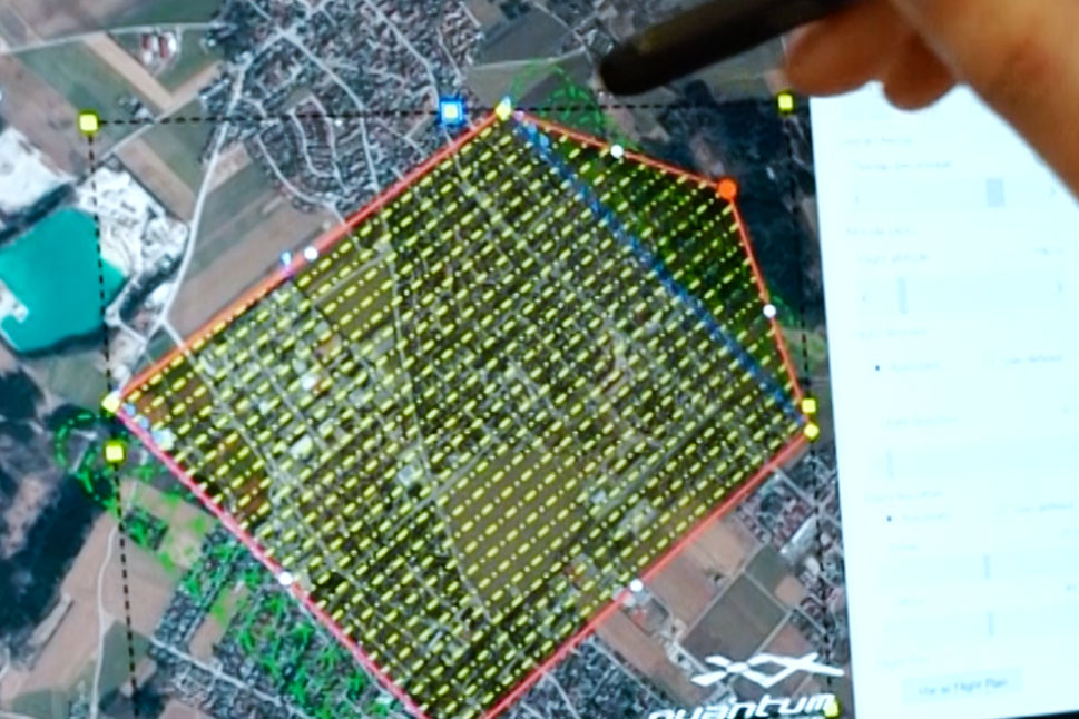 Eine Hand mit Stift zeichnet an einem Bildschirm einen Bereich ein, der durch die Drohne elektronisch erfasst wurde.