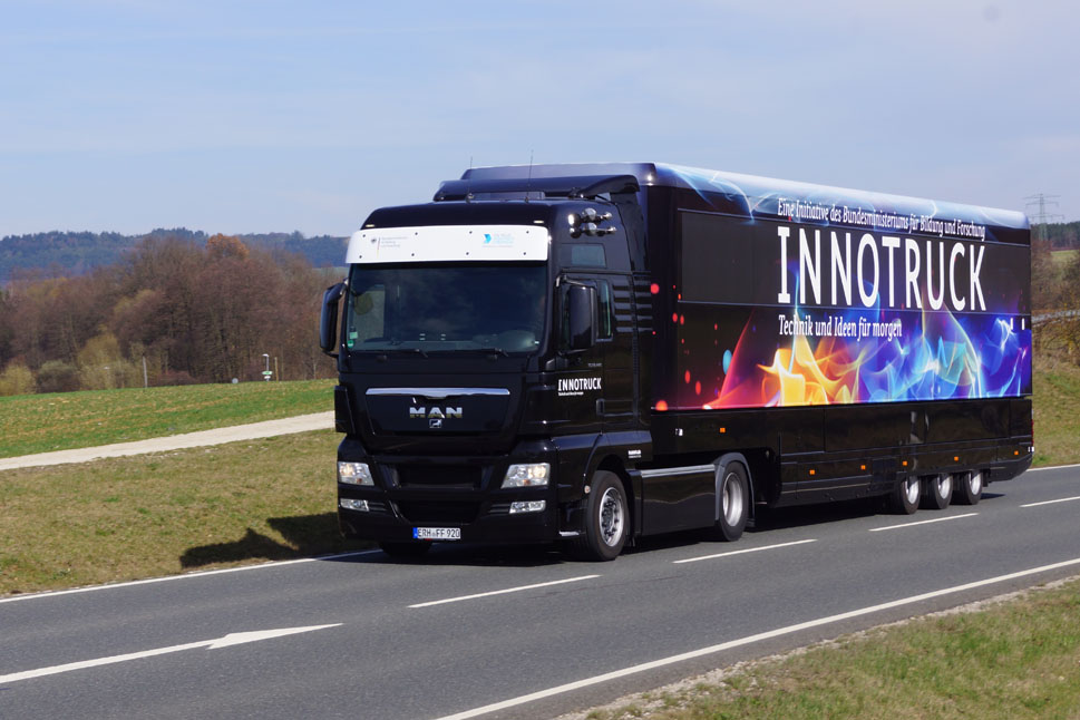Ein auff&auml;llig gestalteter Sattelzug mit Aufschrift "Innotruck" fahrend auf einer Landstra&szlig;e.